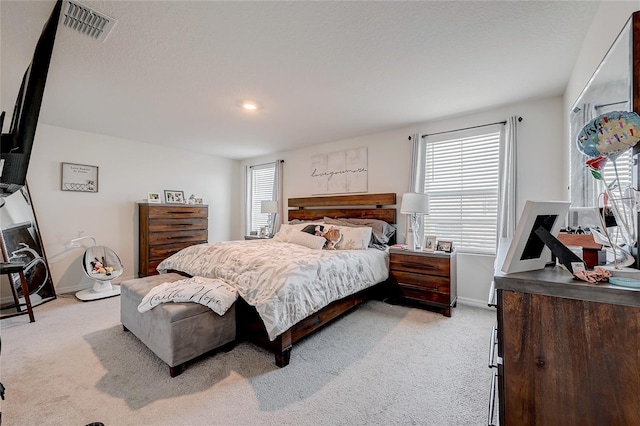 bedroom featuring light colored carpet, visible vents, and multiple windows