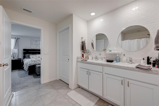 bathroom with double vanity, visible vents, a sink, and tile patterned floors