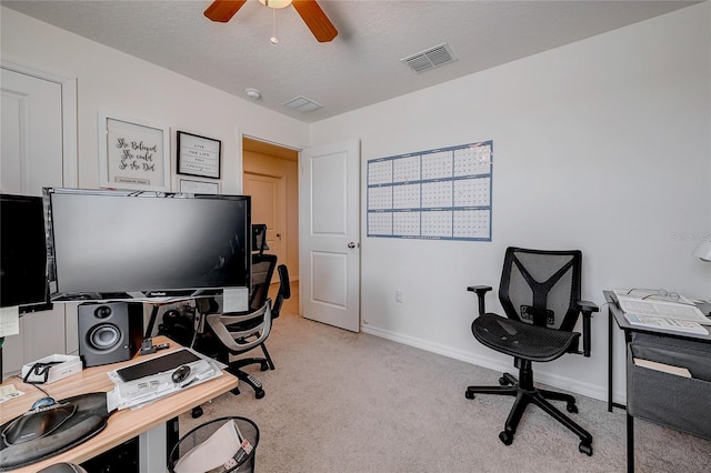 office space with baseboards, visible vents, light colored carpet, ceiling fan, and a textured ceiling