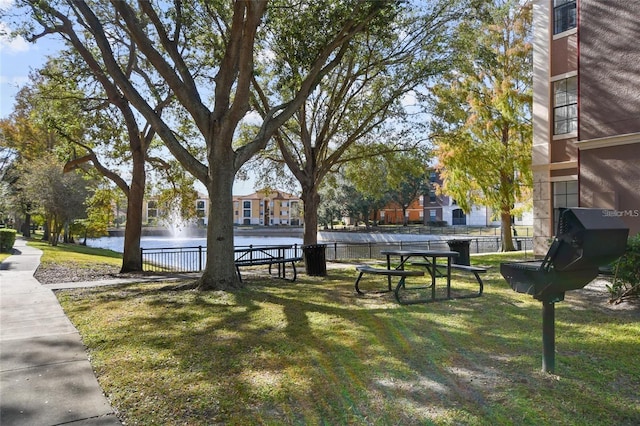 surrounding community featuring a water view, a yard, and fence