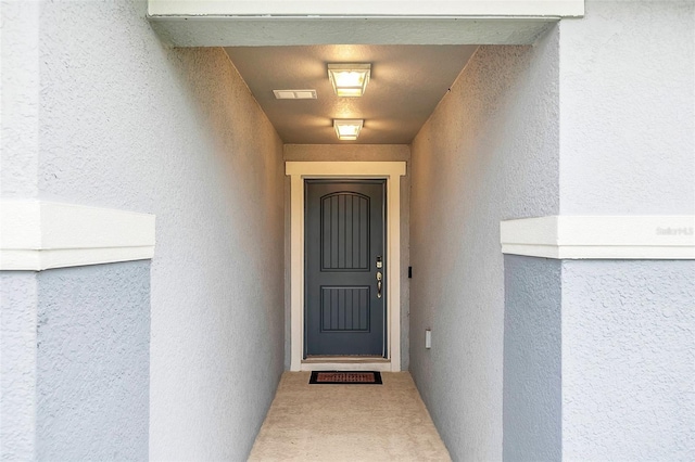 entrance to property with visible vents and stucco siding