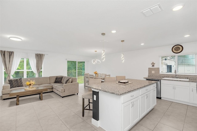 kitchen with visible vents, dishwasher, a kitchen island, a breakfast bar area, and open floor plan