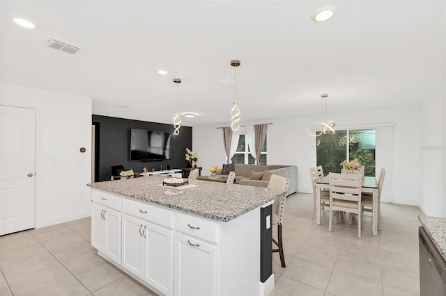 kitchen with a kitchen island, white cabinetry, open floor plan, stainless steel dishwasher, and pendant lighting