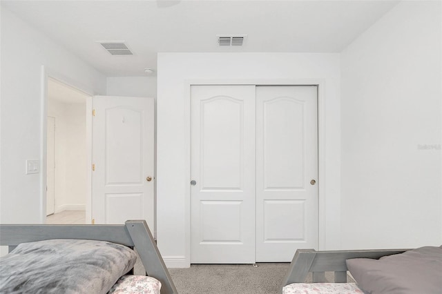 bedroom featuring a closet, visible vents, light carpet, and baseboards