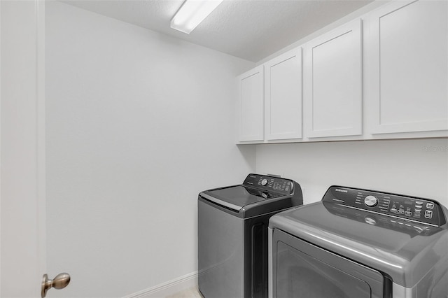 washroom with washing machine and dryer, cabinet space, and baseboards