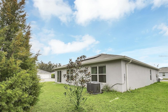 view of home's exterior featuring stucco siding, central AC, and a yard