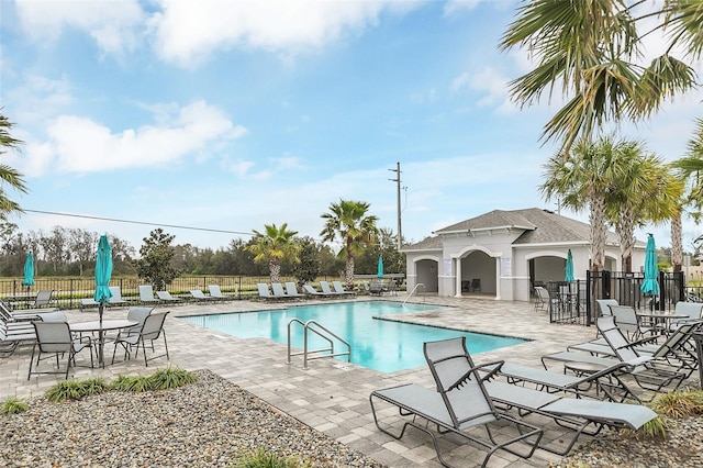 pool with a patio area and fence