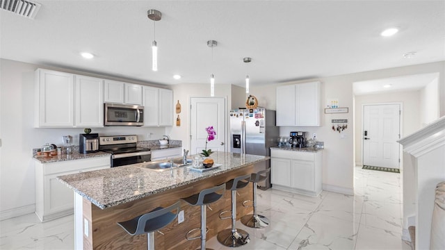 kitchen featuring baseboards, appliances with stainless steel finishes, a breakfast bar, marble finish floor, and white cabinetry