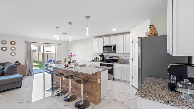 kitchen featuring stainless steel appliances, a sink, white cabinetry, open floor plan, and marble finish floor