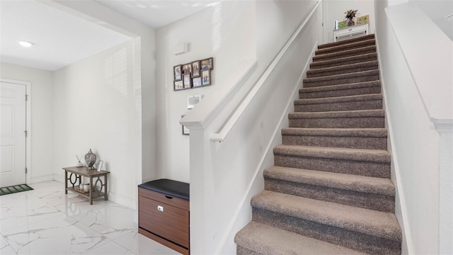 stairway featuring marble finish floor and baseboards