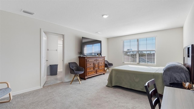 bedroom featuring baseboards, ensuite bathroom, visible vents, and light colored carpet