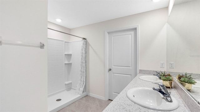 bathroom featuring a stall shower, double vanity, a sink, and tile patterned floors