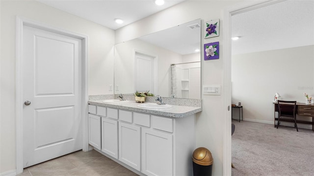 bathroom featuring tile patterned floors, walk in shower, a sink, and double vanity