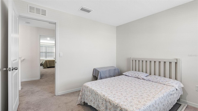 bedroom with baseboards, visible vents, and light colored carpet