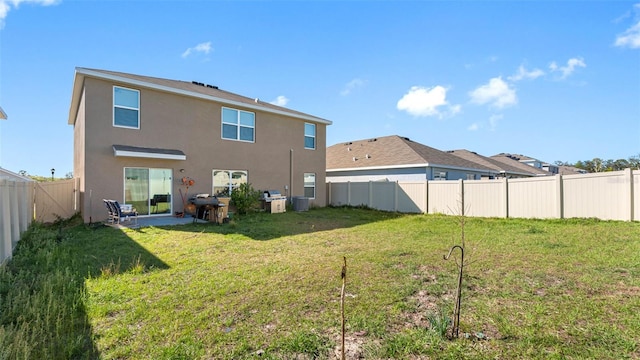 back of house with a fenced backyard, a lawn, and stucco siding