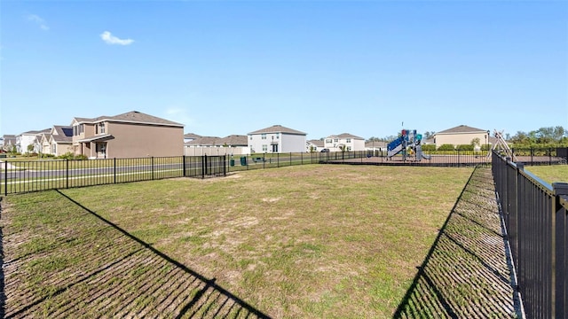 view of yard featuring a residential view, playground community, and fence