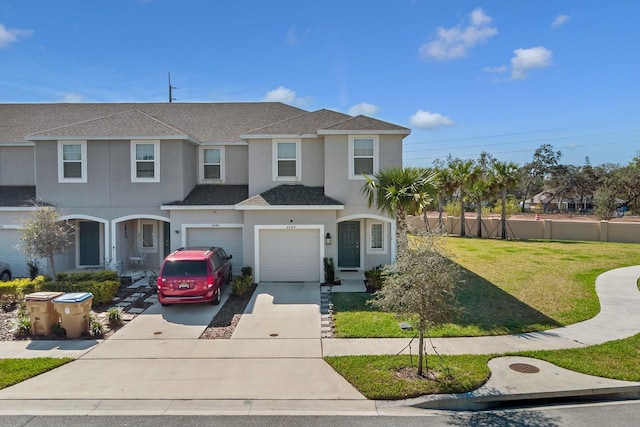 view of front facade with an attached garage, driveway, roof with shingles, stucco siding, and a front lawn