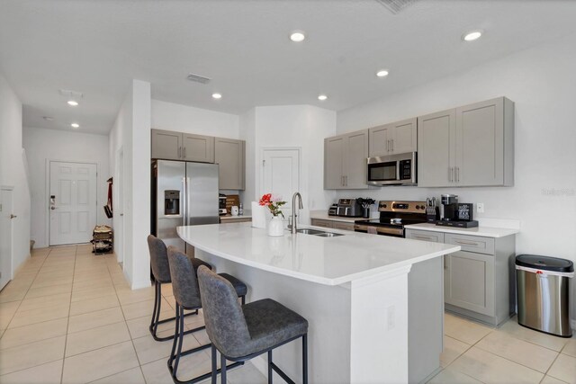 4544 Teoli Ct, Kissimmee, FL 34746 - kitchen featuring a kitchen island with sink, gray cabinetry, stainless steel appliances, a sink, and light countertops