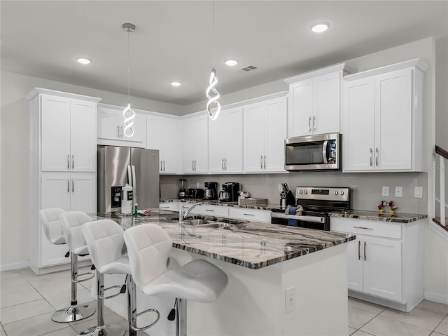 kitchen featuring pendant lighting, a center island with sink, appliances with stainless steel finishes, white cabinetry, and a sink