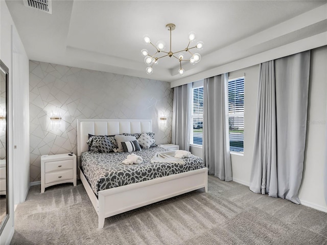 carpeted bedroom with an inviting chandelier, visible vents, a tray ceiling, and baseboards