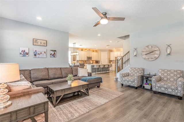 living area featuring ceiling fan, stairway, wood finished floors, a textured ceiling, and recessed lighting