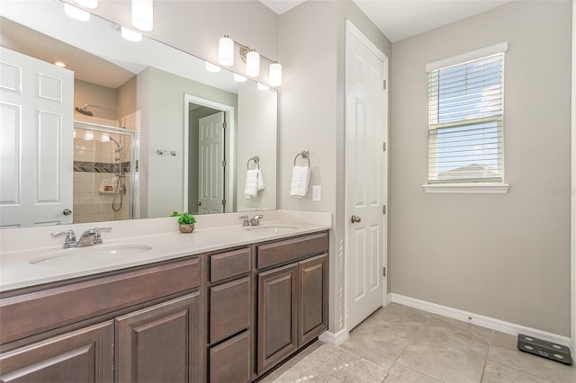 full bath featuring double vanity, a stall shower, a sink, and baseboards