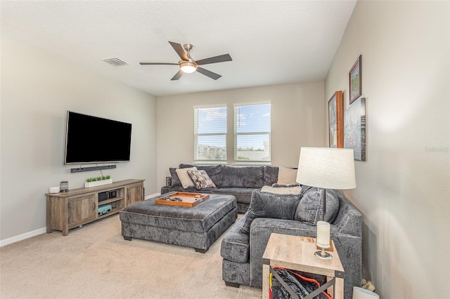 living room with visible vents, baseboards, light colored carpet, ceiling fan, and a textured ceiling