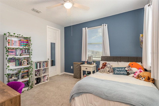 bedroom with ceiling fan, a textured ceiling, light colored carpet, visible vents, and baseboards