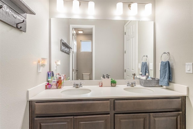 bathroom featuring a sink, toilet, and double vanity