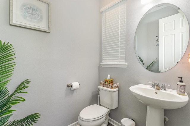 bathroom featuring toilet, baseboards, and a sink