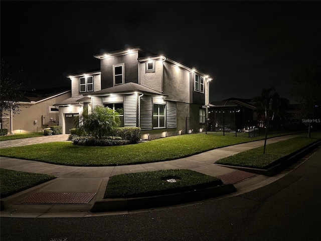 view of front facade with a garage, a yard, driveway, and stucco siding