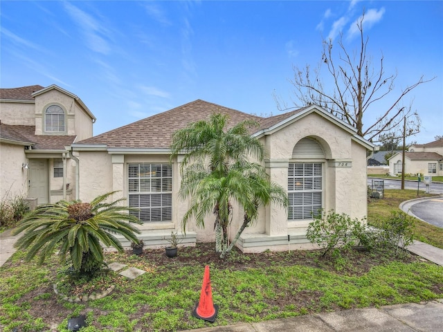 view of front of house with a shingled roof and stucco siding