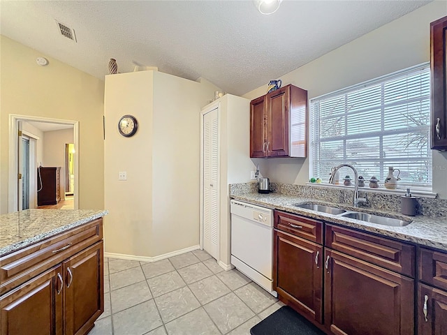 kitchen with light tile patterned floors, visible vents, dishwasher, light stone counters, and a sink