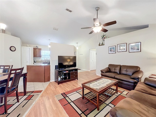 living room featuring vaulted ceiling, ceiling fan, light wood-style flooring, and visible vents