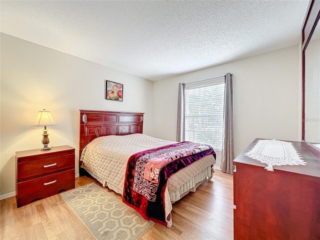 bedroom with a textured ceiling and light wood-style floors