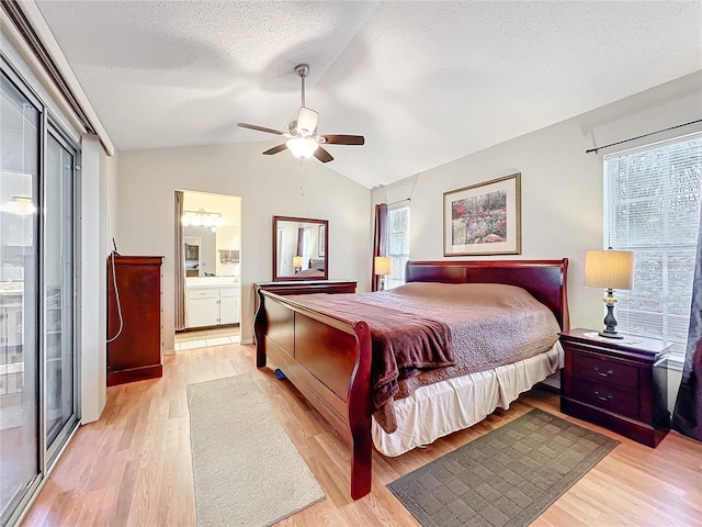 bedroom featuring lofted ceiling, light wood-style floors, connected bathroom, a textured ceiling, and ceiling fan