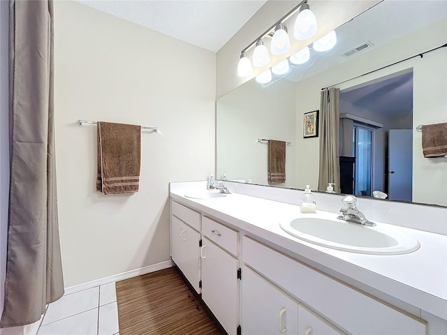 bathroom featuring double vanity, baseboards, visible vents, and a sink