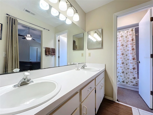 bathroom featuring wood finished floors, visible vents, a sink, and double vanity