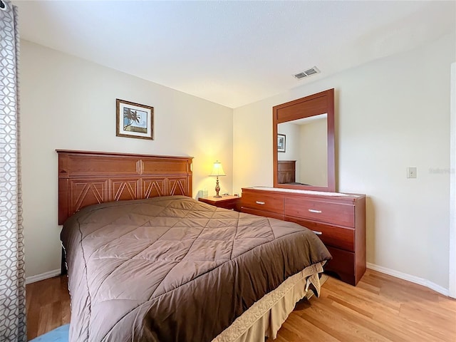 bedroom featuring light wood-type flooring, visible vents, and baseboards