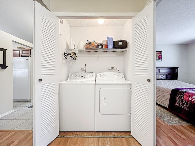 clothes washing area with light wood-style floors, washing machine and dryer, laundry area, and a textured ceiling