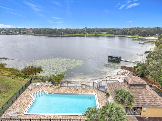 community pool with a water view and fence