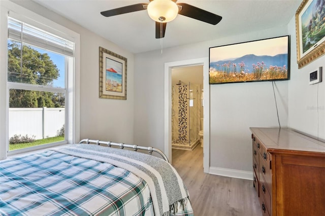 bedroom with ceiling fan, connected bathroom, light wood-style flooring, and baseboards