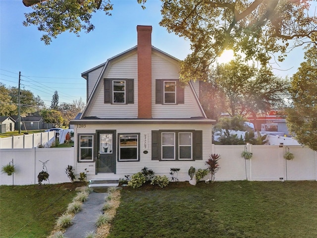 view of front of house featuring a front yard, fence, and a gambrel roof