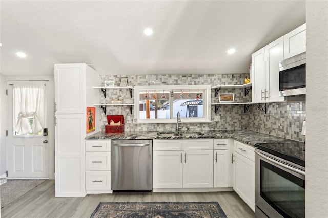 kitchen with stainless steel appliances, white cabinets, a sink, and open shelves