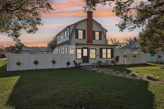 back of house with a yard, fence, and a gambrel roof