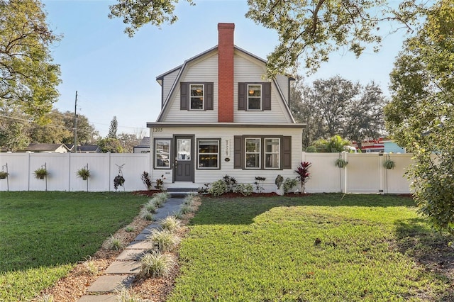 dutch colonial featuring a front yard, a fenced backyard, a chimney, and a gambrel roof