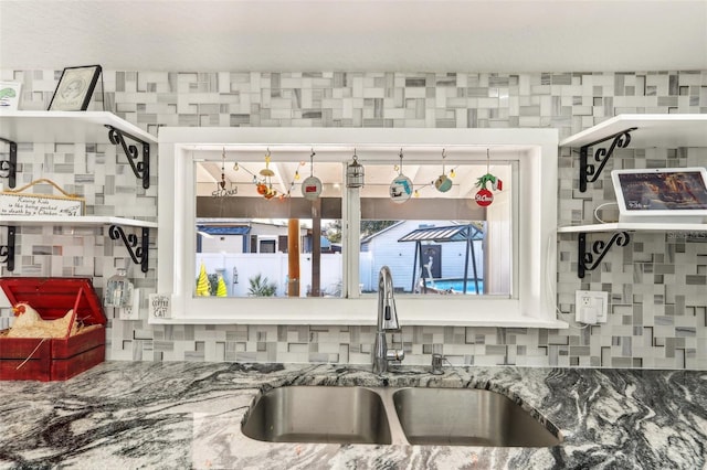 interior space featuring stone counters, a sink, and decorative backsplash