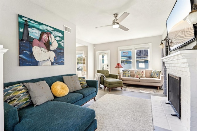 living room with a fireplace, wood finished floors, visible vents, and a ceiling fan