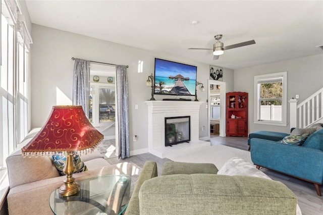 living room with a fireplace, wood finished floors, visible vents, a ceiling fan, and stairs