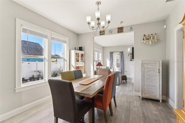 dining room with a chandelier, light wood-style flooring, and baseboards